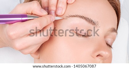 Microblading eyebrows. Cosmetologist making permanent makeup. Attractive woman getting facial care and microblading