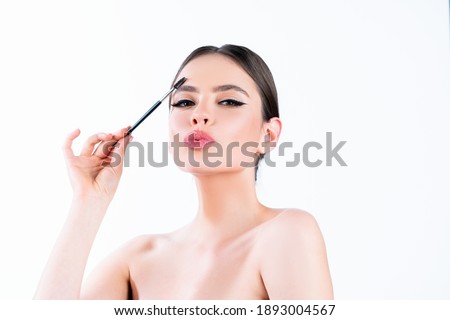 Microblading, modeling brows, perfection concept. Attractive gorgeous charming lady with ideal face, healthy shiny clear skin, amazing hairstyle, holds brush in hand, paint her eyebrows
