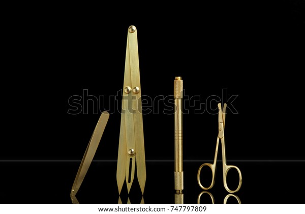 Microblading tools for drawing eyebrows;\
toolkit includes blade holder, golden ratio divider or compass,\
scissors and tweezers on a black\
background