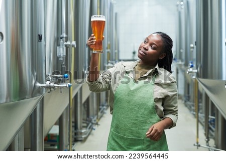 Microbrewery worker checking quality of produced beer