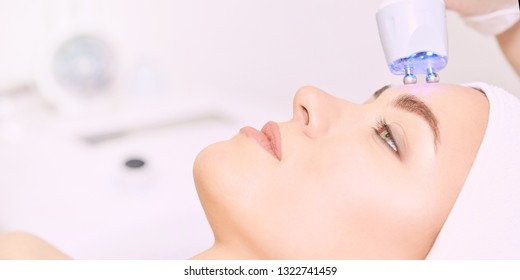 Microcurrent Light Esthetics Procedure. Beauty Girl Face. Cosmetology Machine. Doctor Hands. Two Micro Balls. Wrinkle Reduction.