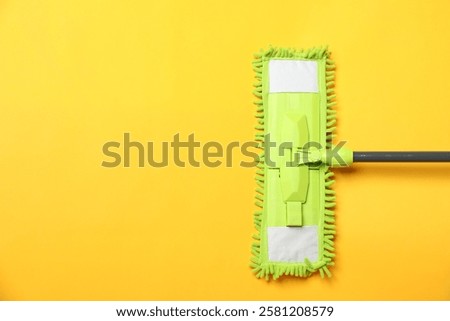 Microfiber mop on yellow background, top view. Space for text