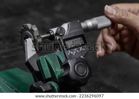 micrometer digital quality control check cutter cutting tool roundness in workshop. use screw gauge calipers analogue. quality control concept.