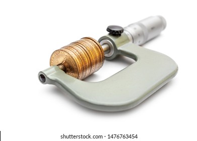 Micrometer with golden coins on a white background. Business concept.