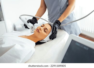 Microneedle RF lifting procedure. Hardware cosmetology. Beautician conducts a facial rejuvenation procedure for a brunette woman - Shutterstock ID 2291189005