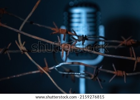 Microphone behind barbed wire as a symbol of discrimination, free speech crisis, political persecution and repression. Selective focus on barbed wire