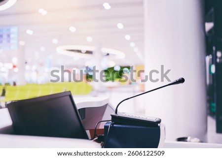 A microphone and computer setup at an information desk in a brightly lit public area.