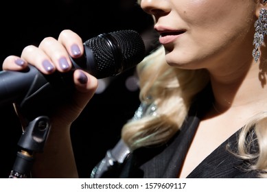 Microphone And Female Singer Close Up. Woman Singing Into A Microphone, Holding Mic With Two Hands.