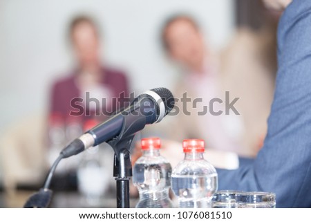 Microphone in focus against blurred people at round table event