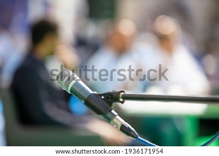 Microphone in focus against blurred people at roundtable event