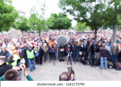 Microphone In Focus Against Blurred Protest Or Public Demonstration