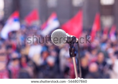 Microphone in focus, blurred crowd in background. Protest. Public demonstration.