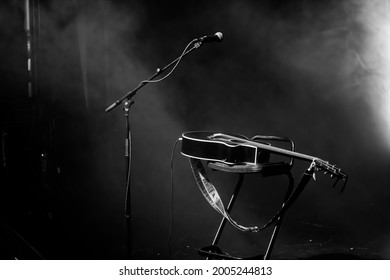 Microphone, Guitar And Stool On A Concert Stage. Black And White High Contrast With Spotlight And Smoke. Live Singing Performance. Music Show Background. Spotlight Smoke Empty Stage.