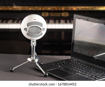 Microphone And Laptop With A Piano On Background. Set Up For Online Music Lessons.