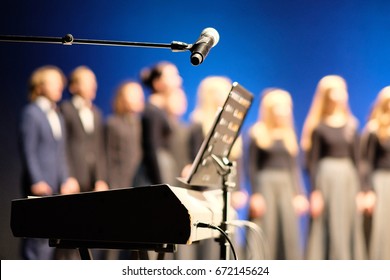 Microphone and music stand in front of electric pianos on the stage of the theater