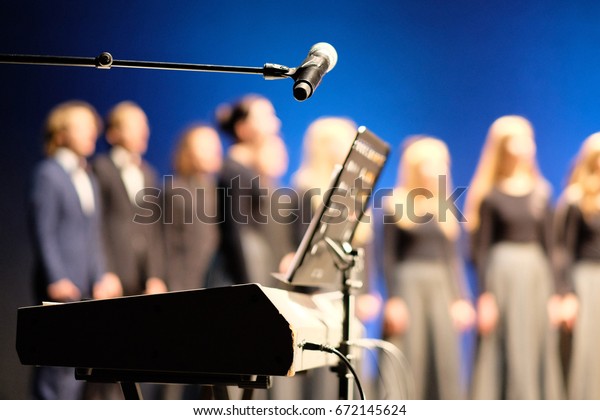 Microphone and music stand in front of electric\
pianos on the stage of the\
theater