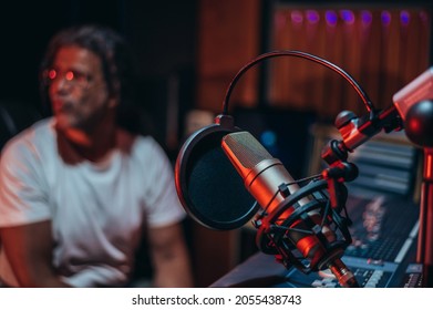 Microphone in music studio with the music producer sitting in the background