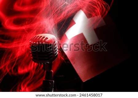Microphone on a background of a blurry flag of Switzerland close-up. dark table decoration. Selective focus