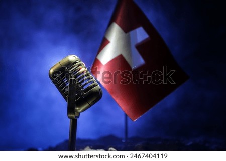 Microphone on a background of a blurry flag of Switzerland close-up. dark table decoration. Selective focus