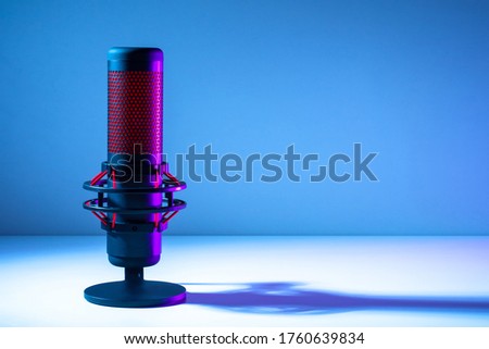Microphone on a blue background. Space for text. Public speech. Sound amplification. Sound technology. Black and red microphone close-up.