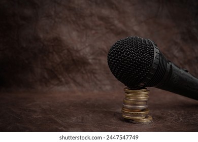 Microphone on a stack of coins on brown leather background, podcast revenue concept, close up