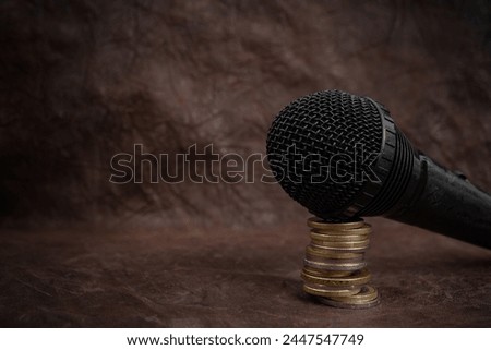 Microphone on a stack of coins on brown leather background, podcast revenue concept, close up