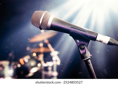 Microphone on stage – live showbiz music setting featuring close up of vocal mic for singing. Drum kit and stage lighting in background. Performance venue such as concert, festival, night club or bar. - Powered by Shutterstock