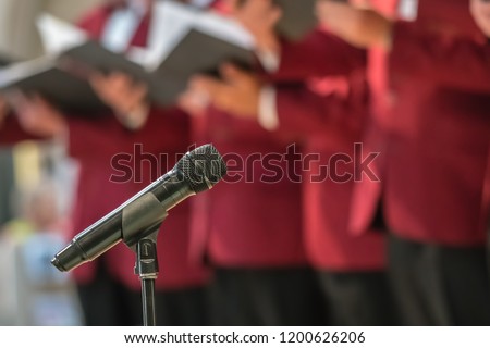 Microphone on a stand in front of mens choir members holding singing book while performing in a cathedral in Rochester, Kent, UK