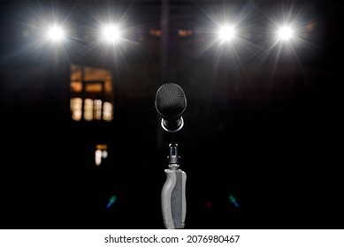 Microphone on the stand with hand nozzle in the center tage with beautiful bokeh spotlights in the background. High quality photo
