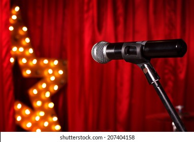 Microphone On Theater Stage ,golden Star On Background  With Red Curtains 