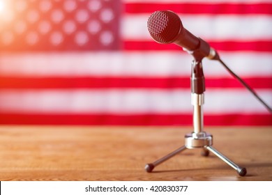 Microphone On US Flag Background. Table With Microphone And Banner. Radio Show About To Begin. Good Morning, Fellow Citizens.