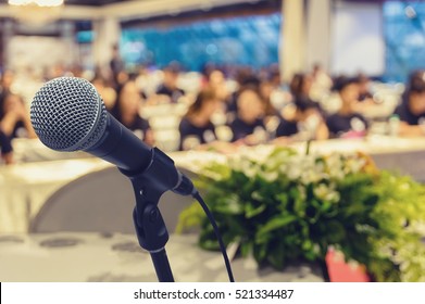 Microphone over the Abstract blurred photo of conference hall or seminar room with attendee background, business seminar concept