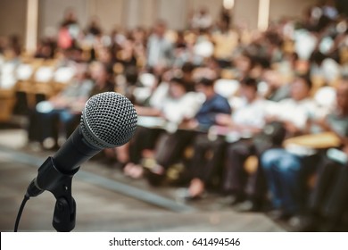 Microfone sobre a foto desfocada abstrata da sala de conferências ou sala de seminários com fundo do participante