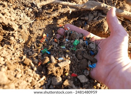 Microplastic pollution. Microplastics in ground. Soil contaminated with microplastics. Plastic waste in soil, earth. Environmental, groundwater disaster. Plastic waste in ground at agricultural field.
