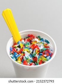 Microplastic In White Plastic Cup With Spoon. Light Grey Background. Microplastic Problem Concept. Place For Text, Close Up