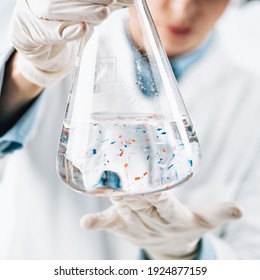 Microplastics laboratory analysis. Scientist observing microplastics or tiny plastic particles in a flask with a water sample.