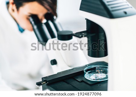 Microplastics Laboratory Research. Scientist using a microscope to analyze and quantify plastic particles in a water sample 