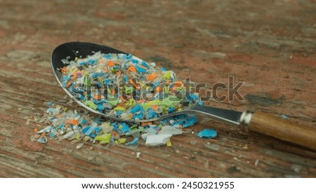Microplastics in a spoon. A concept of consuming micro plastic particles, water and soil pollution.