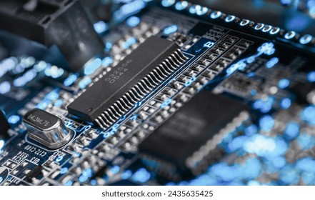 A microprocessor on a printed circuit board surrounded by auxiliary elements, backlit through the board. Macrofto in dark colors
