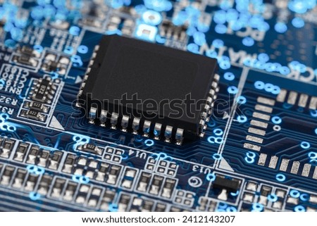 A microprocessor on a printed circuit board surrounded by auxiliary elements, backlit through the board. Macrofto in dark colors
