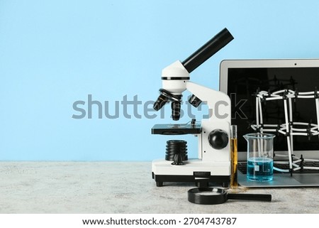 Microscope with laptop, molecular model and flasks of samples on blue background. Nobel Prize Day