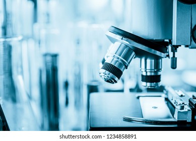 Microscope in microbiology lab with laboratory glassware background for medical research or science development concept.