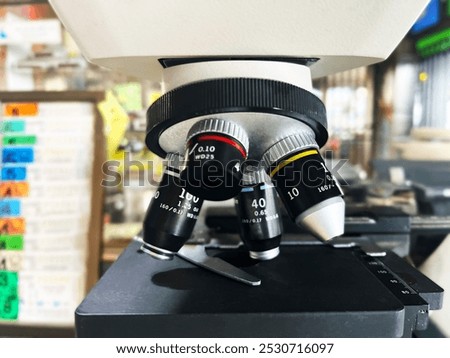 microscope, microscope's objective lenses, clearly displaying the different magnifications labeled 10x, 40x, and 100x, laboratory equipment, scientific research, biology, microscopy