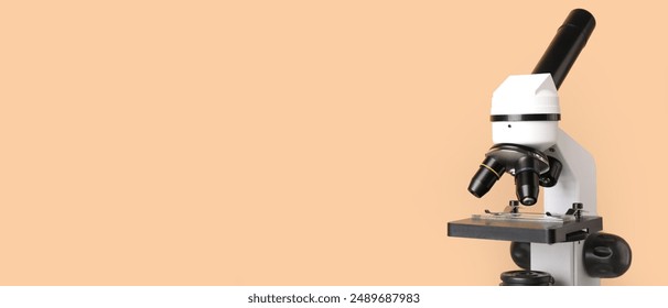 Microscope on beige background with space for text