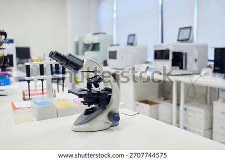 Microscope on lab counter surrounded by scientific equipment in a modern laboratory setting