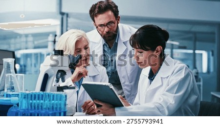 Microscope, science and tablet with team in laboratory together for development or research. App, feedback and talking with scientist people at work on clinical trial, medical industry or study