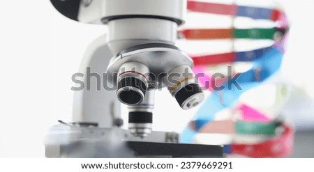 Microscope standing near multicolored model of dna chain in lab. Screening for hereditary genetic diseases concept