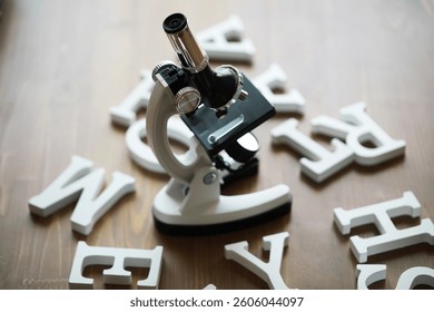 Microscope Surrounded by Scattered Letters on Wooden Table - Science and Education Concept
