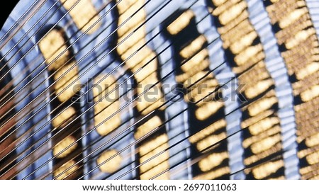 Microscopic view of diagonal gold wire bonds in IC packaging, showing parallel wire array connecting chip to substrate with blue and gold bonding pads in semiconductor assembly.