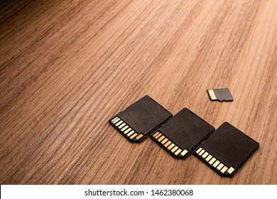 Microsd card, technology products. Photograph of three adapters and a micro sd card on a wooden object. - Shutterstock ID 1462380068